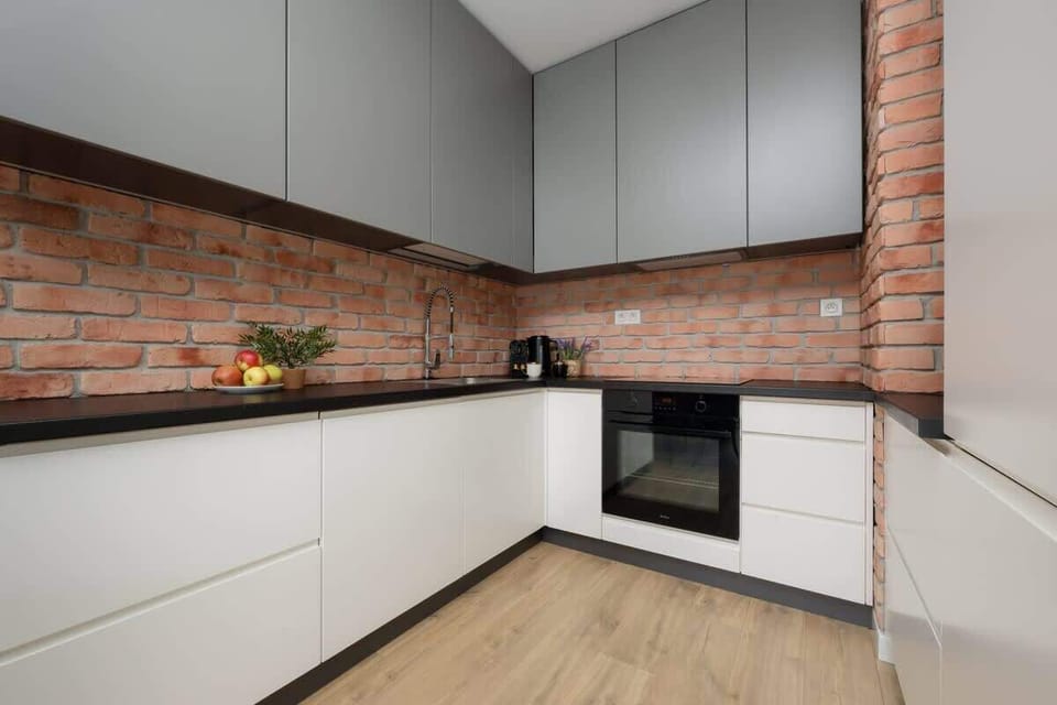 A compact, modern kitchen with white cabinetry and clean wood flooring, blending into an open layout.