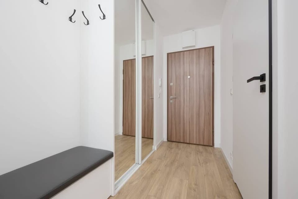 An entrance hallway with wood and white decor, a bench, and minimalist lighting for a modern welcome.