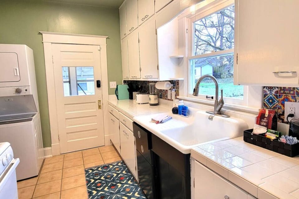 Galley Kitchen and Laundry Area: Efficient galley kitchen with stackable washer and dryer, offering convenience and style – Springfield, MO Bungalow Rental.