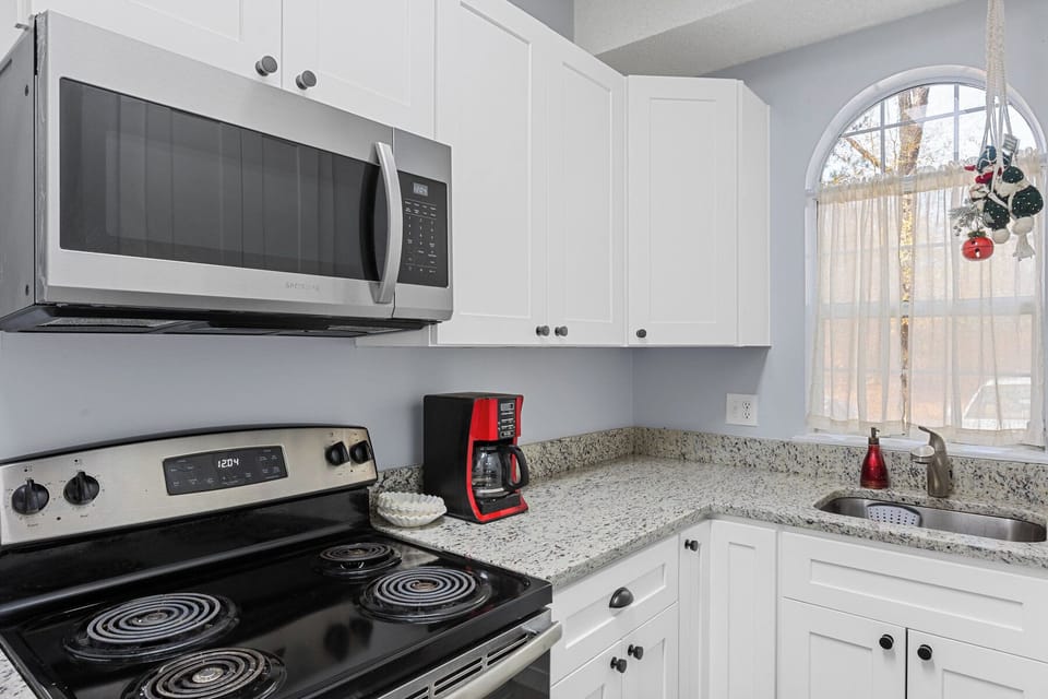 Modern and sunny kitchen with granite countertops, stainless steel appliances.