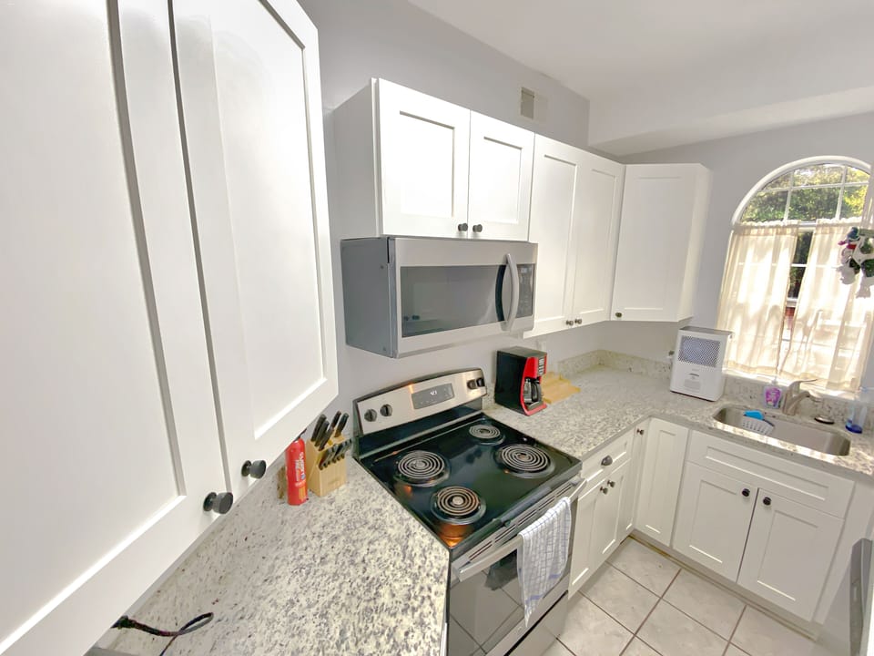 Modern and sunny kitchen with granite countertops, stainless steel appliances.