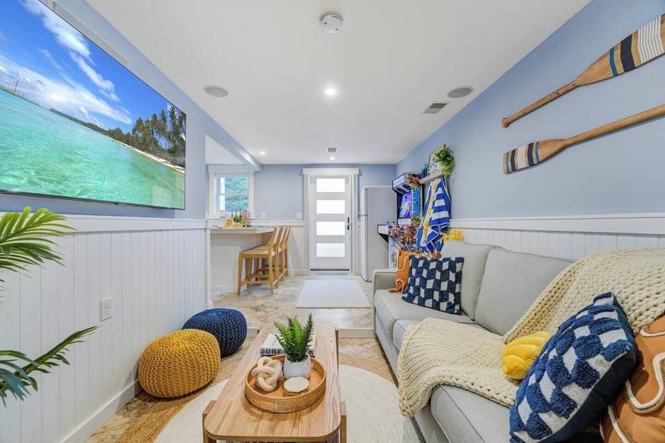 Relax in the comfortable living area adorned with beach-themed décor, vibrant colors, and plenty of natural light for a serene and inviting ambiance.