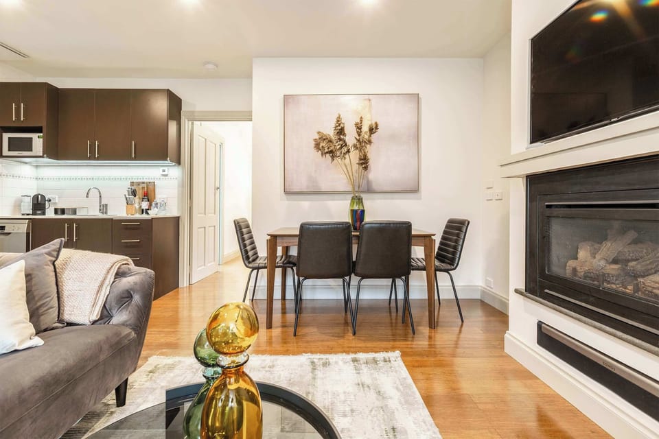 DINING: Modern comfort meets warm elegance. Enjoy a stylish open plan living space with a cozy fireplace, sleek kitchen, and inviting dining area, perfect for relaxing evenings or shared meals.