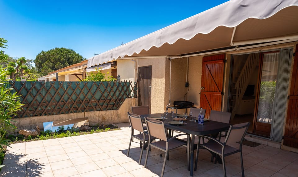 Outside terrace with electric grill, dining table and awning.