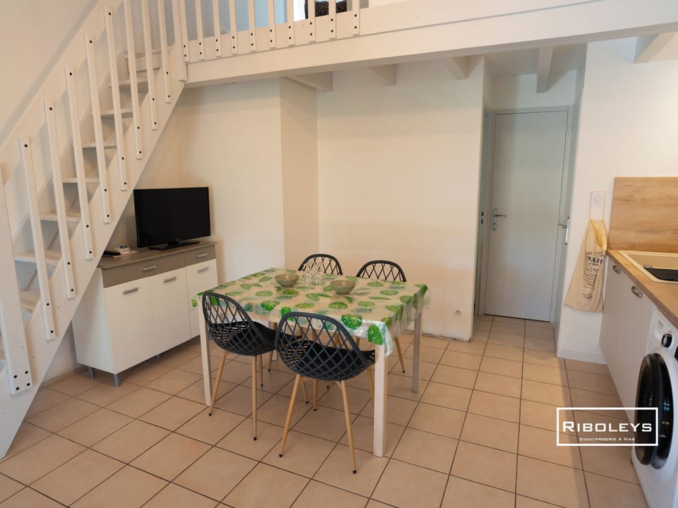 Air-conditioned living room with fitted kitchen, dining table and TV.