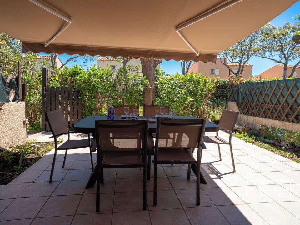 Outside terrace with electric grill, dining table and awning.