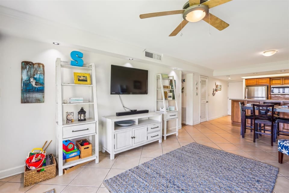 - Entertainment is easy with a flat screen TV, open shelving, and board games for all ages
- Bright white furnishings and coastal accents tie together the beachy living area
- Nearby sliding doors open to outdoor seating and oceanfront lawn