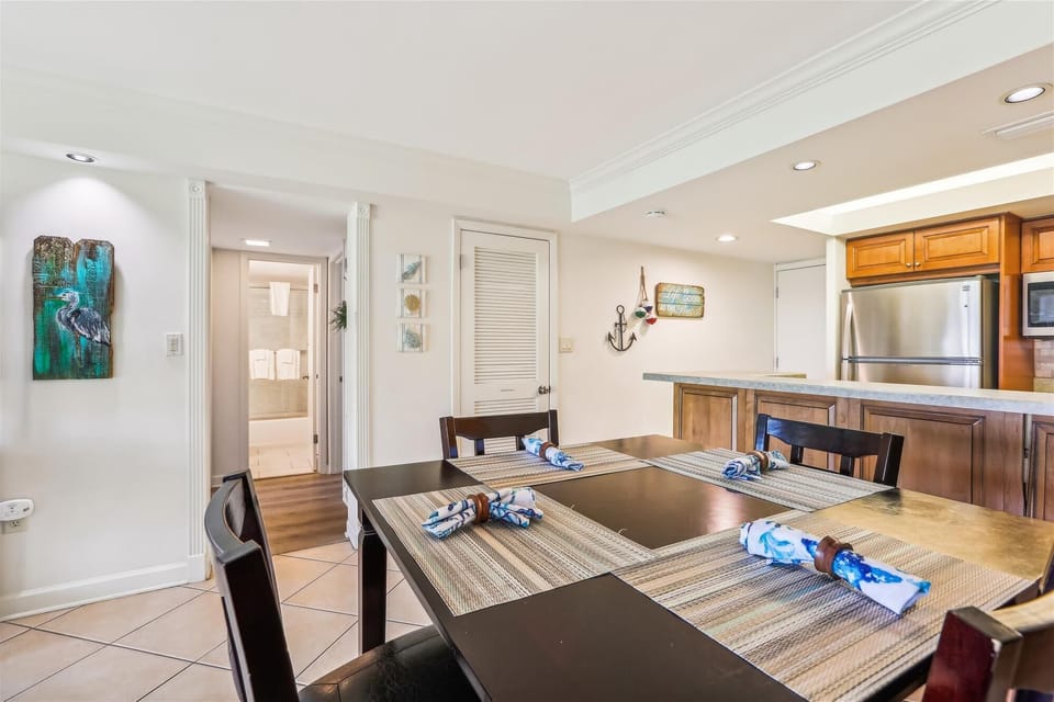 - View from the dining table shows easy access to the hallway and back bedrooms
- Nautical wall decor and recessed lighting add charm to this clean and functional layout
- Open kitchen bar makes serving meals or snacks easy and efficient