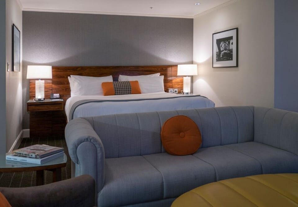 Junior Suite with a tranquil sleeping area, including a king bed and a sofa bed tucked in a cozy nook, perfect for families or groups.