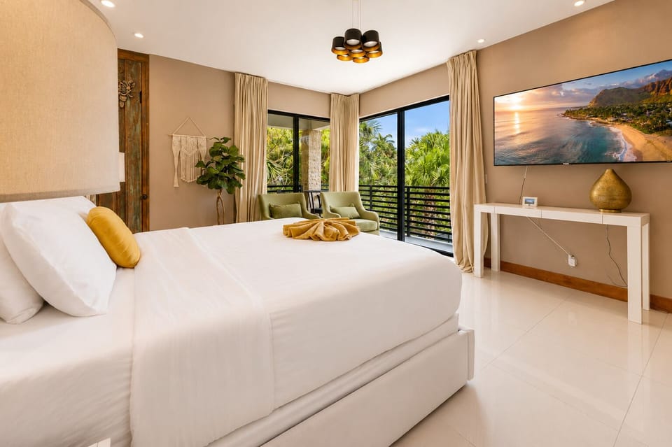 Bright modern king bedroom with tropical views and cozy seating nook