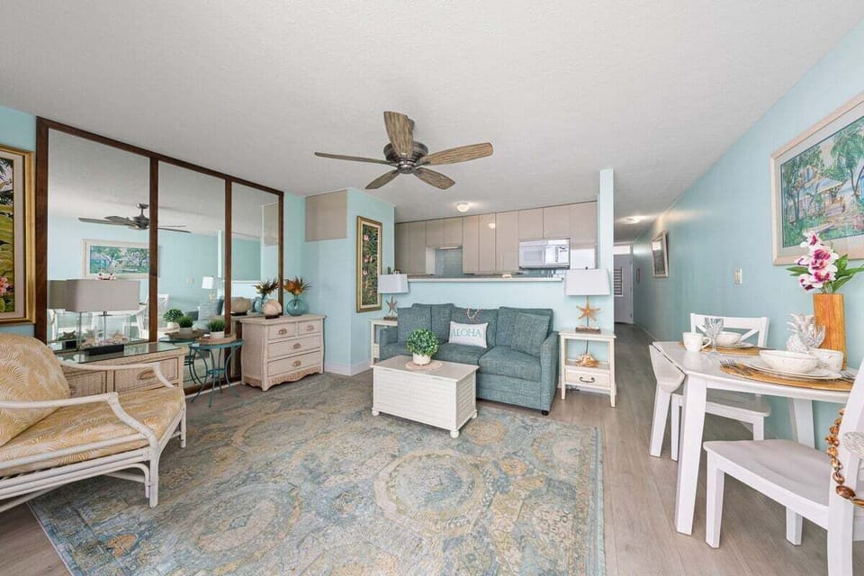 A wider view of the living space with mirrored accents, extra seating, and relaxed coastal styling.