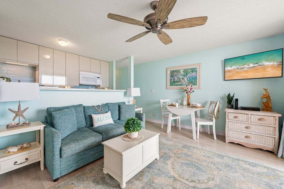 A cozy living area with a blue sofa, beach‑inspired décor, and a small dining nook that feels bright and welcoming.