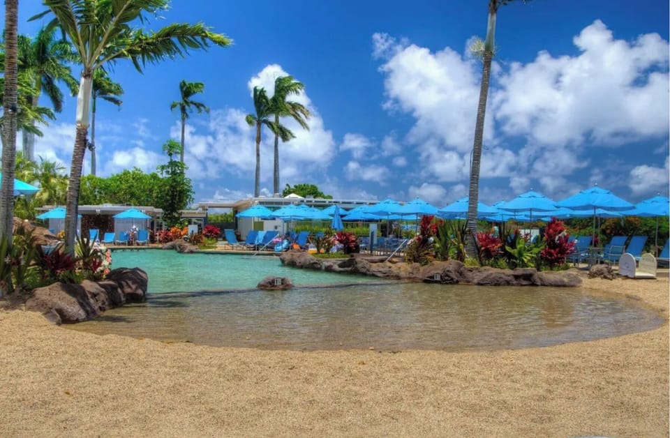 Wade into the shallow keiki end with the little ones while the rest of the group claims a shaded lounger nearby.
