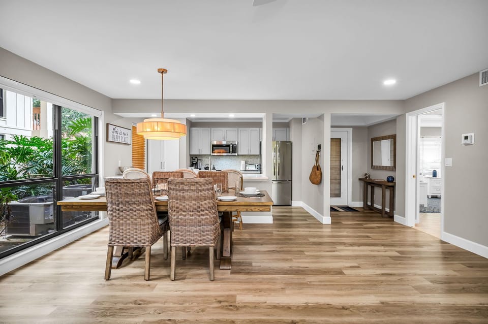 Luxury wooden dining table with 6 rattan dining chairs, and 2 additional counter stools at the kitchen counter.