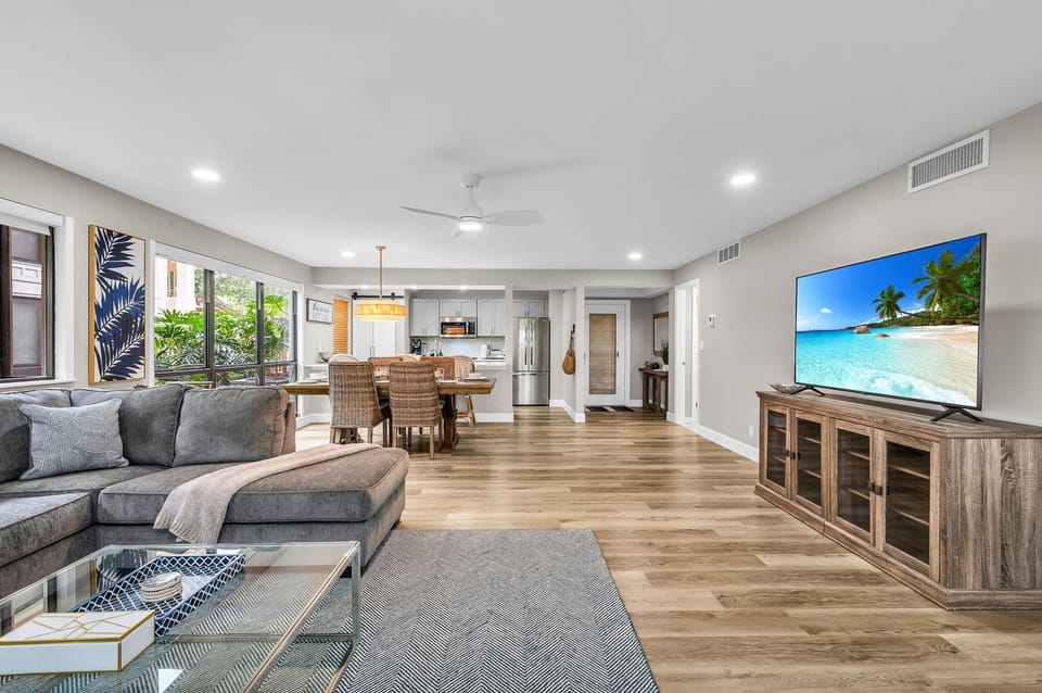 Modern living: Open concept living & dining area with large windows for ample natural light, and views for the golf course. The living room features a full-sized sleeper sofa, personal desk, and smart streaming TV with cable.