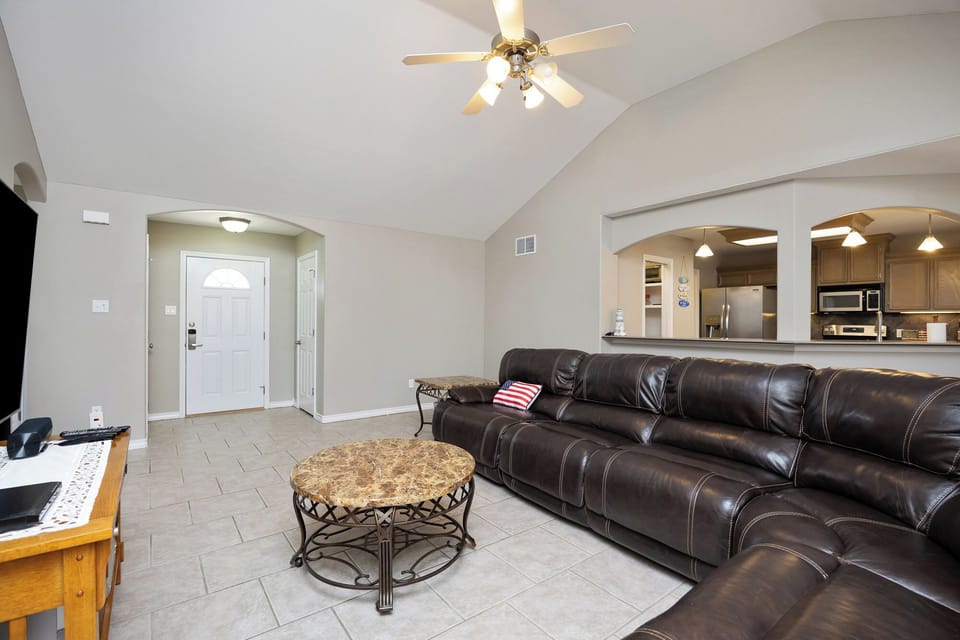 Relax in your spacious living room with plush leather seating, vaulted ceilings, and an open view to the modern kitchen.