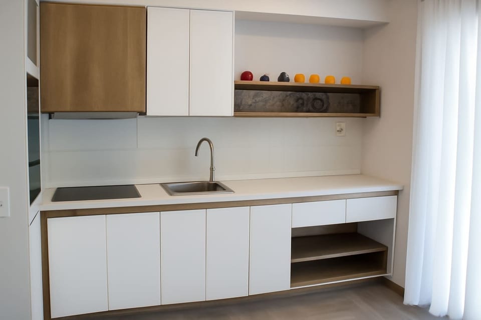 Kitchenette with overhead storage – Functional space with essential appliances and natural wood accents.