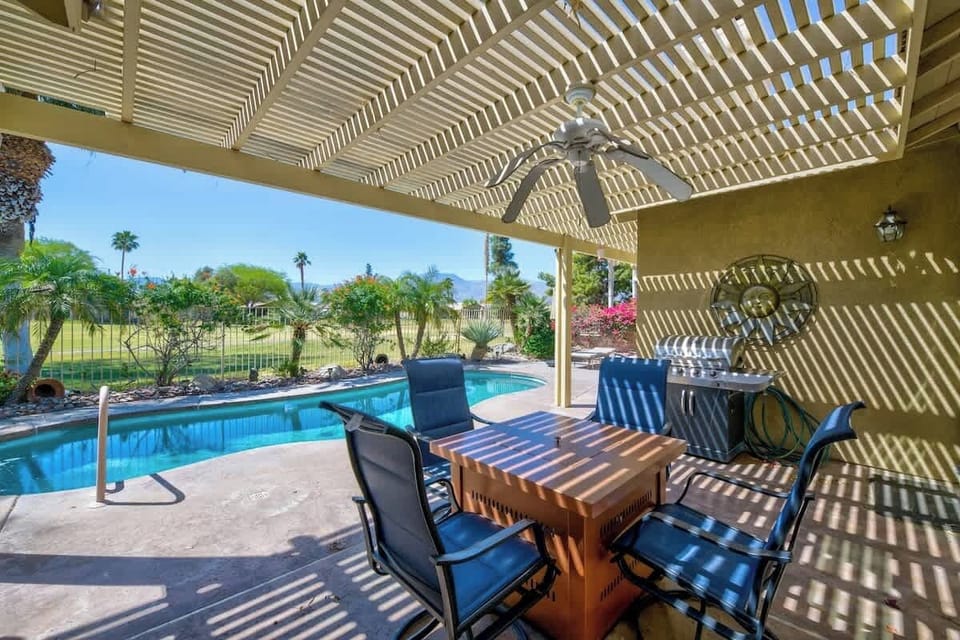 A spacious covered patio with outdoor dining, poolside seating, and scenic views all around.