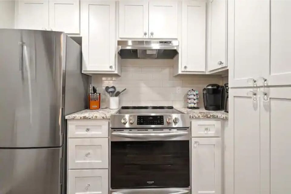 Stocked kitchen including cookware, coffee pods, spices, cooking oils.