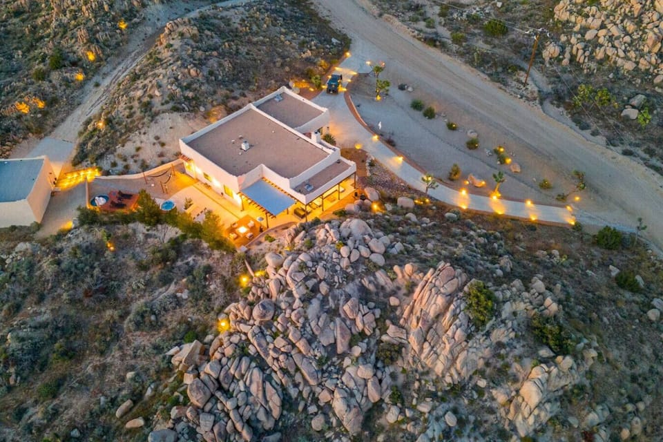 Perched on ancient boulders, glowing against the desert night — your private compound sits atop the Mojave like it was always meant to be there