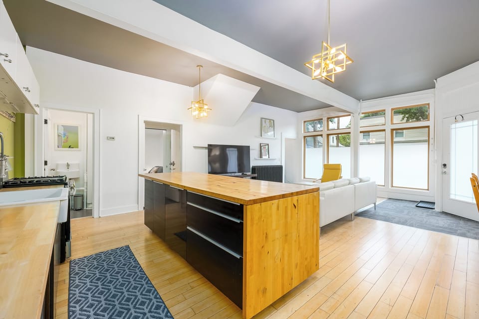 Kitchen opens to living room with bar seating, large TV, half bathroom
