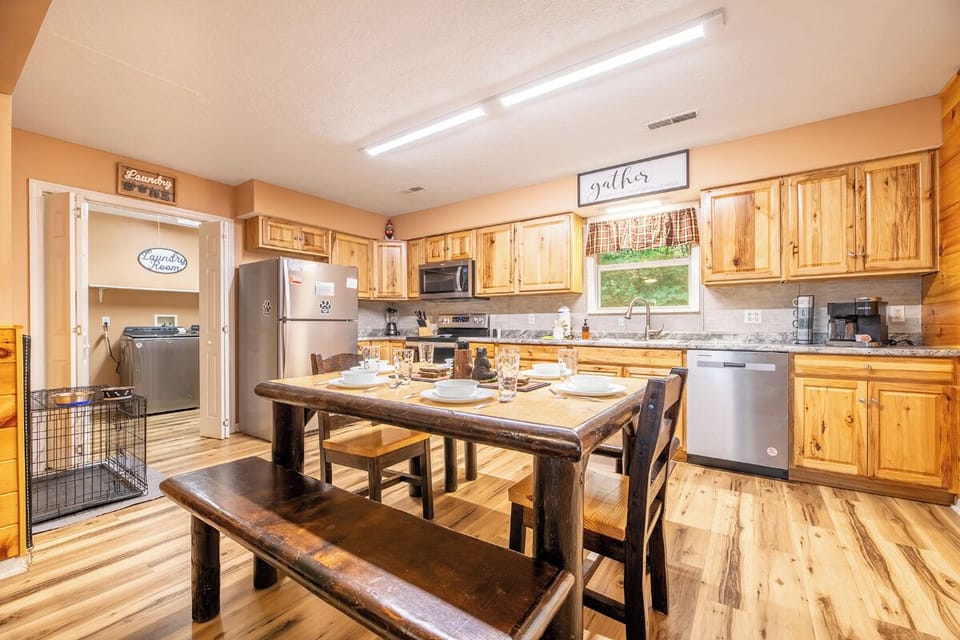 Gather around the rustic dining table in this welcoming kitchen with warm wood cabinetry, modern appliances, and a cozy atmosphere perfect for preparing and sharing your favorite meals.