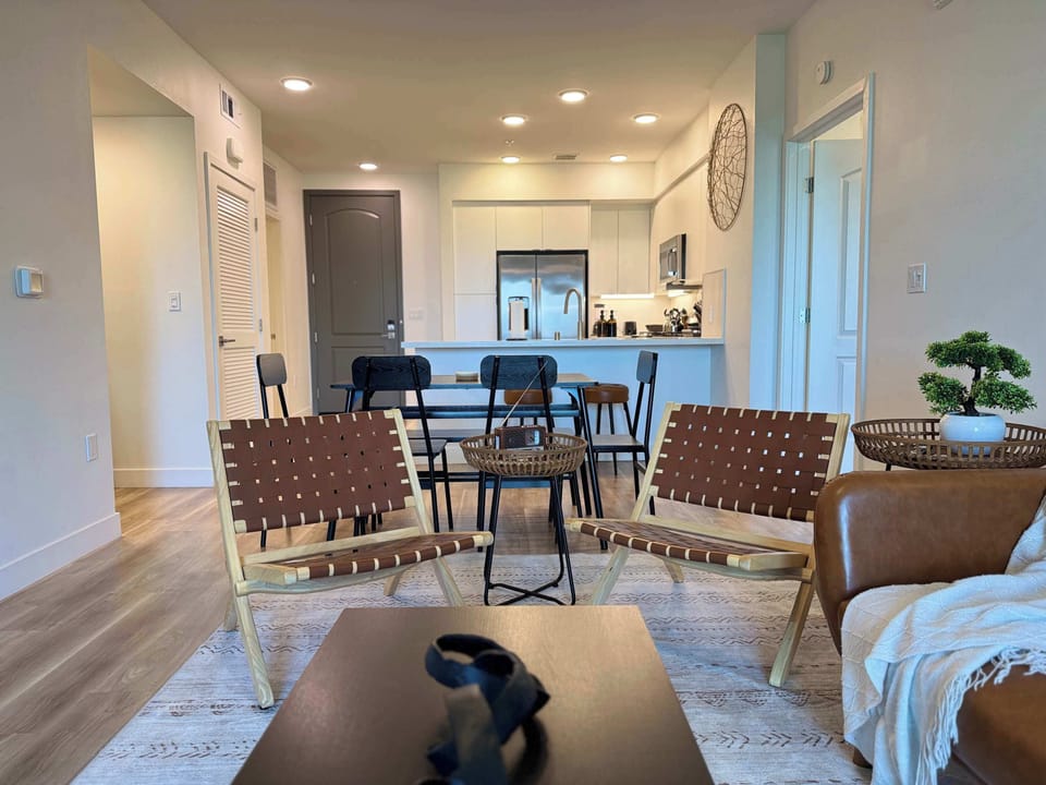 Spacious living room featuring a cozy sofa, two stylish armchairs, a full-size air mattress, and a 65" Smart TV with preloaded access to Netflix, Hulu, and Disney+, all set up for your enjoyment.