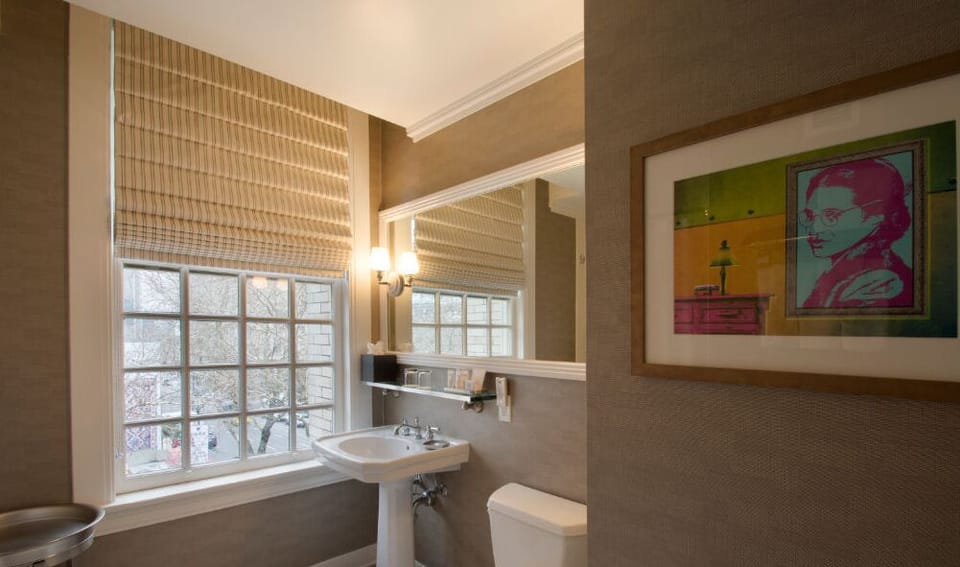 Refresh in the stylish bathroom, featuring modern fixtures, abundant natural light, and chic artwork.