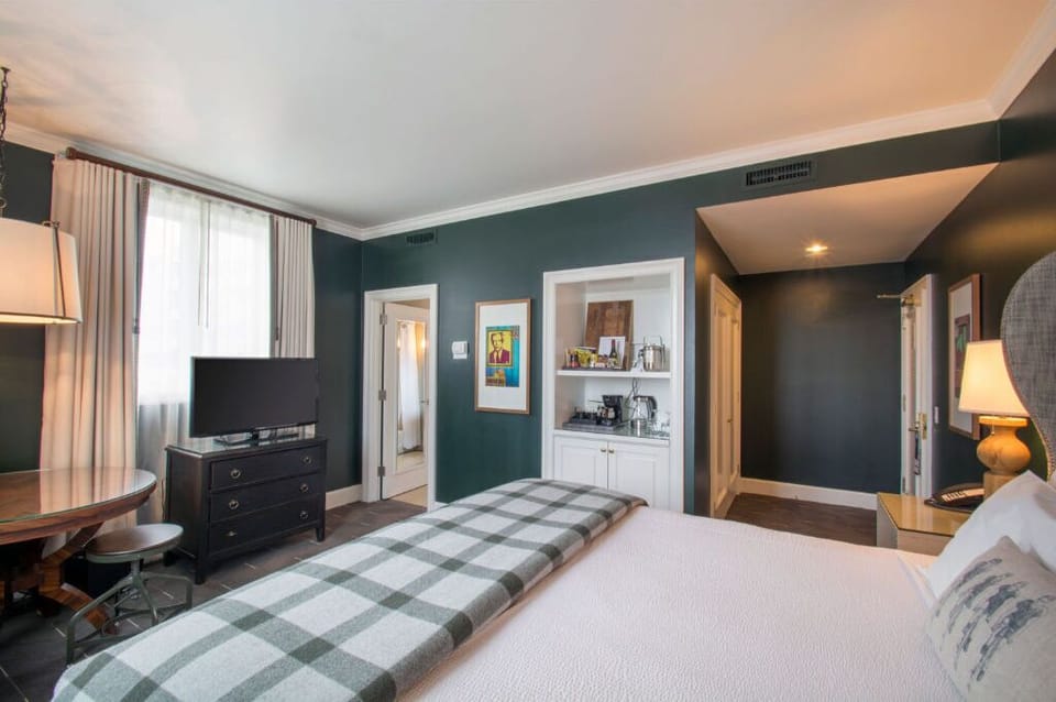 Unwind in this luxurious bedroom featuring a plush king bed, elegant decor, and ample natural light.