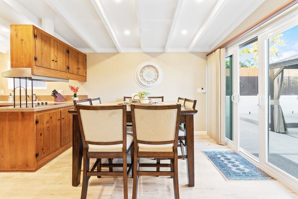Open dining space seating six, flowing seamlessly from the kitchen to a sliding glass door leading straight to the backyard patio.