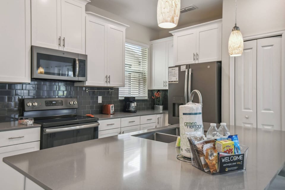 Step into a bright kitchen featuring sleek white cabinetry and a spacious gray countertop, perfect for meal prep. The modern appliances gleam under pendant lighting, creating an inviting atmosphere for culinary adventures.