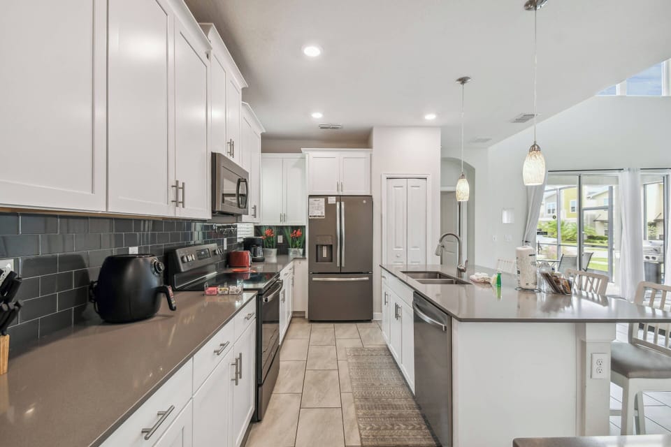 Welcome to this beautiful kitchen featuring sleek white cabinets and rich granite countertops. With a spacious layout and modern stainless steel appliances, it's an inviting, naturally lit space perfect for your culinary.