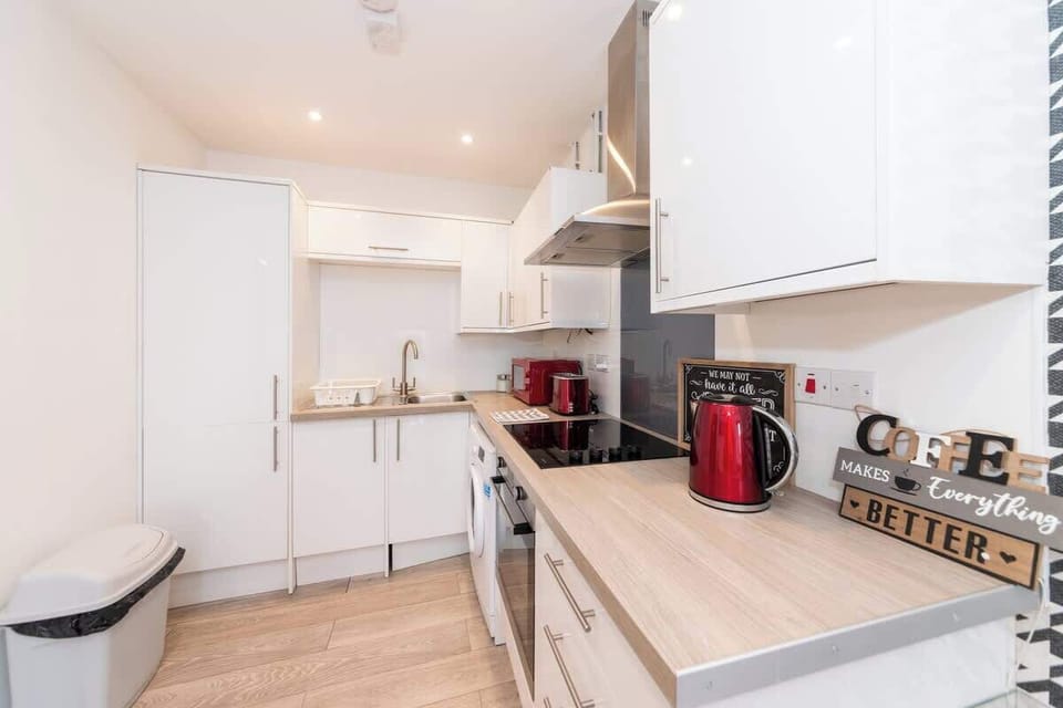 The kitchen features modern white cabinetry, stainless steel appliances, and a sleek countertop 
