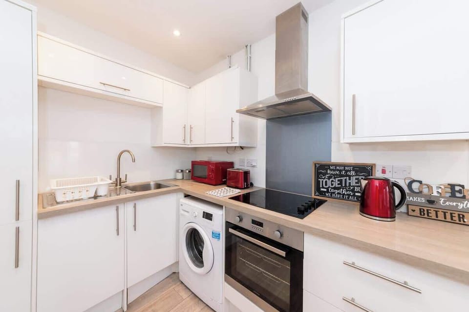 Modern, fully equipped kitchen with sleek white cabinets, built-in appliances, and vibrant red accents for a stylish touch.