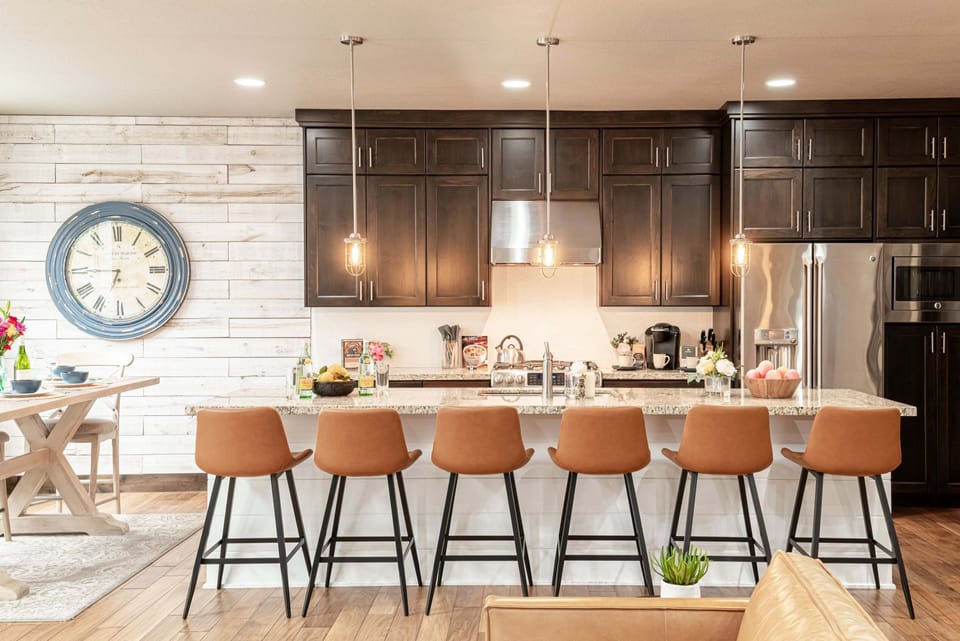 Spacious kitchen boasts stone countertops and a center island with seating for six