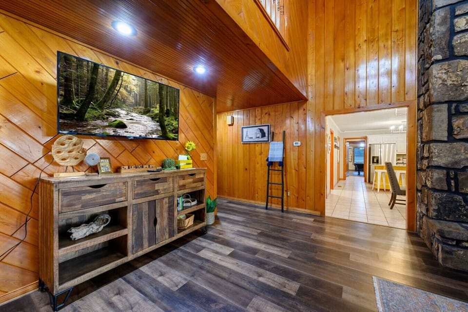 Main living room with stone fireplace and warm wood walls.