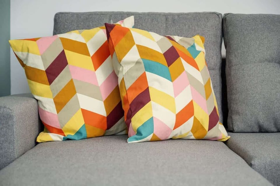 Colorful cushions on the grey sofa bring energy and a cheerful touch to the space, creating a cozy atmosphere.