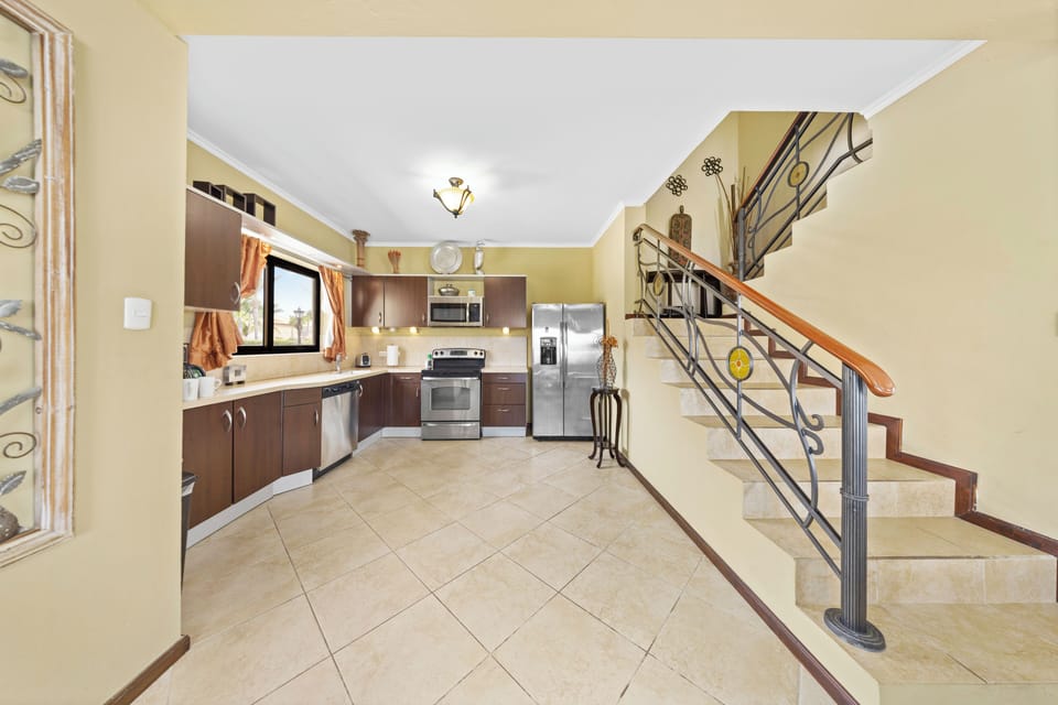 - Discover the seamless integration of the open kitchen and staircase in our townhouse in Noord, Aruba. - Marvel at the architectural beauty of the kitchen bathed with the natural light. - Enjoy the convenience of modern appliances available.