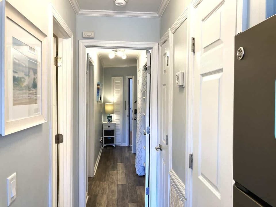 Well-lit hallway with light wood-style flooring that connects the living spaces.