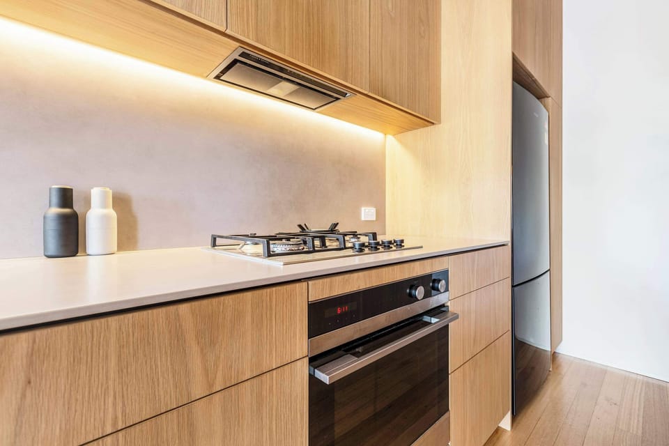 KITCHEN: Featuring rich Tasmanian Oak cupboards stocked with essentials and modern appliances, this kitchen is perfectly equipped for exploring Melbourne’s vibrant culinary scene or enjoying simple, delicious meals at home.