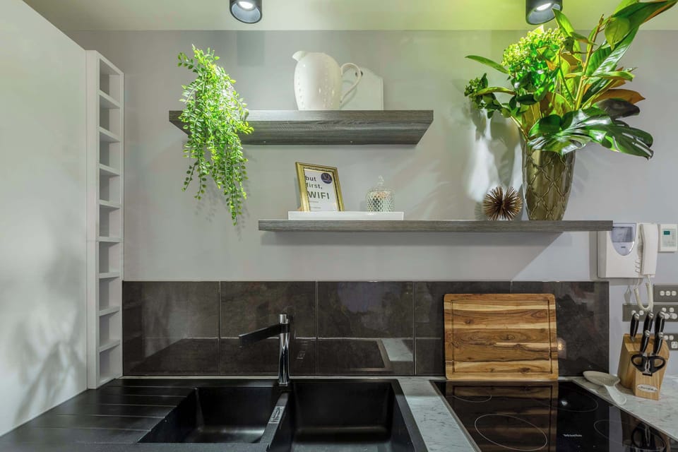 Stylish kitchen corner with modern finishes, open shelving, and lush greenery for a fresh, inviting touch