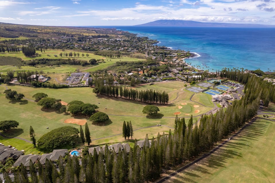Caption: Discover the beauty of Kapalua from above, featuring pristine golf courses, lush landscapes, and sparkling ocean waters.