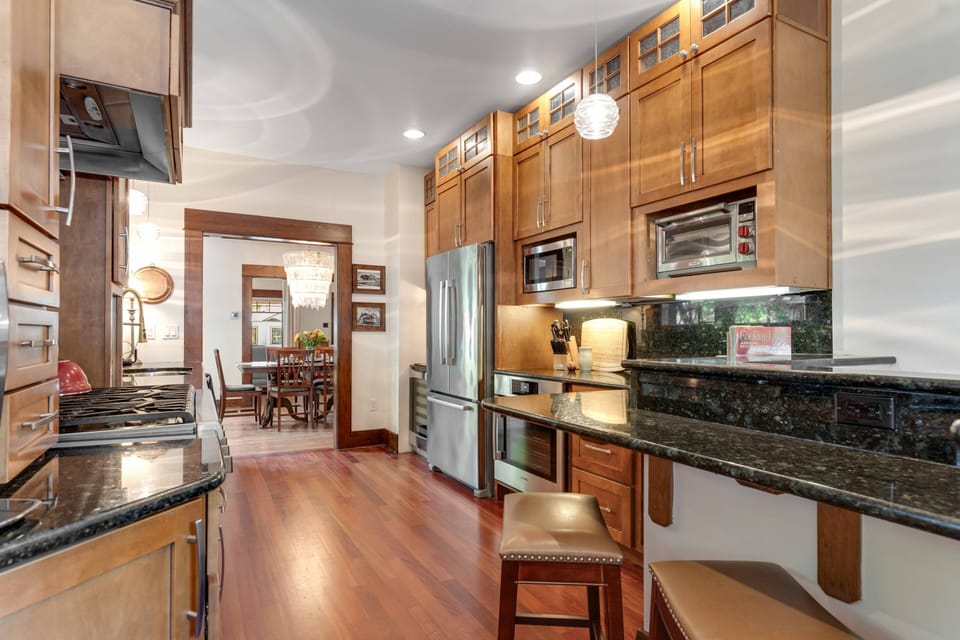 The gourmet kitchen outside features beautiful wood cabinetry, a breakfast bar with seating for 2, granite countertops & more!