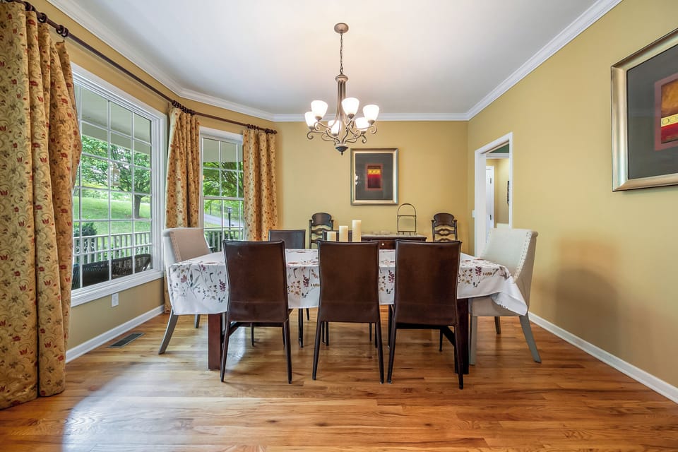 Formal dining room with large windows, a stylish chandelier, and beautiful hardwood flooring