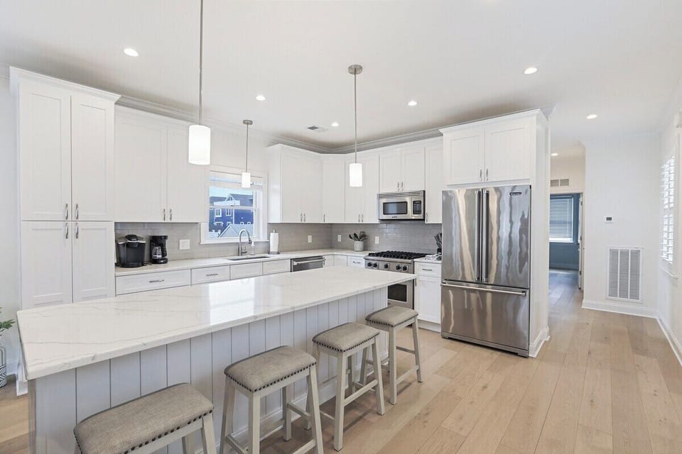 Prepare gourmet meals in this spacious, fully-equipped kitchen, featuring high-end stainless steel appliances and expansive quartz countertops. The large central island with comfortable seating is perfect for casual dining, socializing, or working.