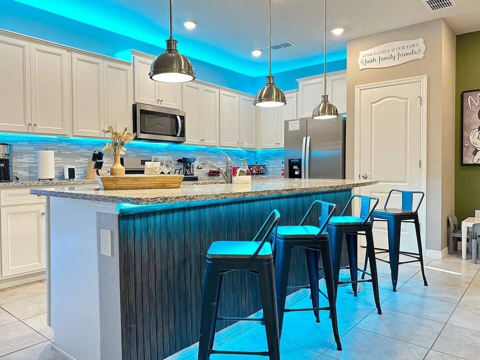 Open-concept kitchen with white cabinetry, granite countertops, and stainless steel appliances.
