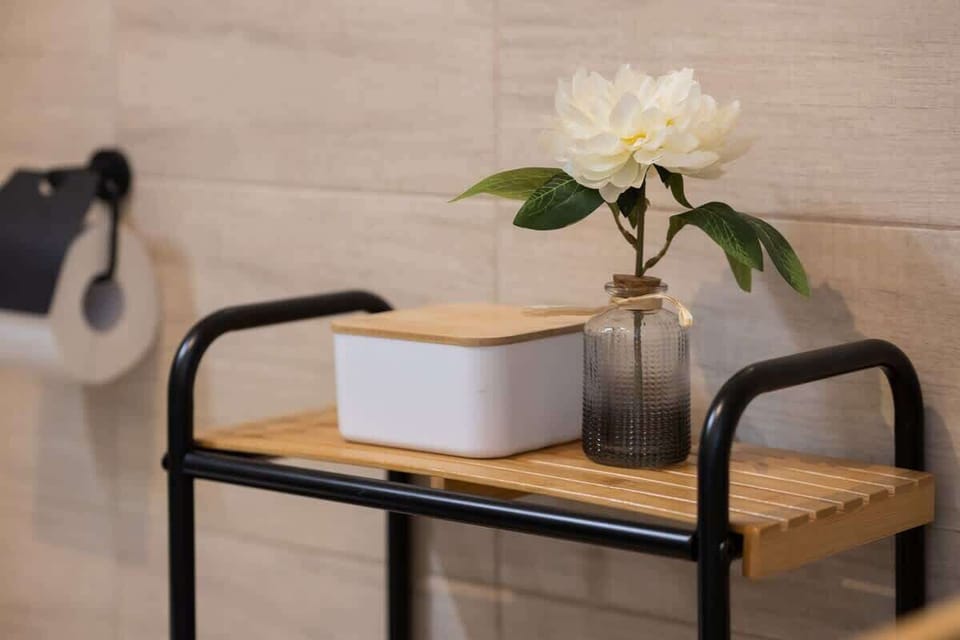 A metal side table with flowers and light accessories brings a touch of freshness and subtle elegance to the bathroom.