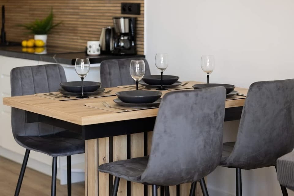 The dining area with a wooden table and dark chairs offers an elegant spot for evening dinners and wine conversations.