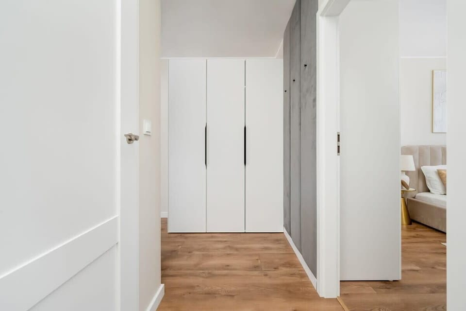 A bright hallway with a built-in wardrobe and wooden flooring greets guests with an elegant, tidy space.