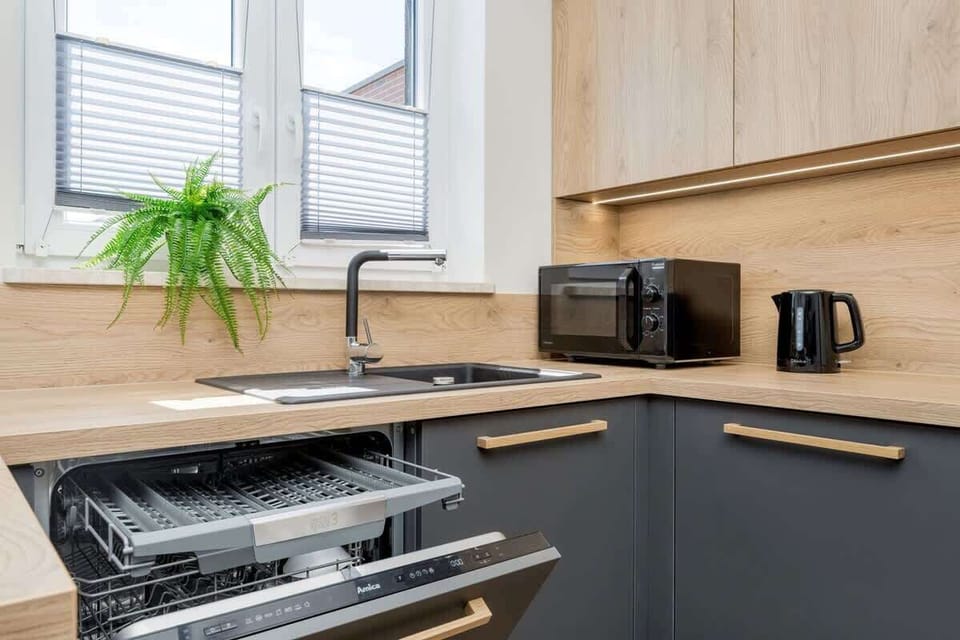 A modern kitchen with a wooden countertop, full appliances and a large window offers both functionality and natural light.
